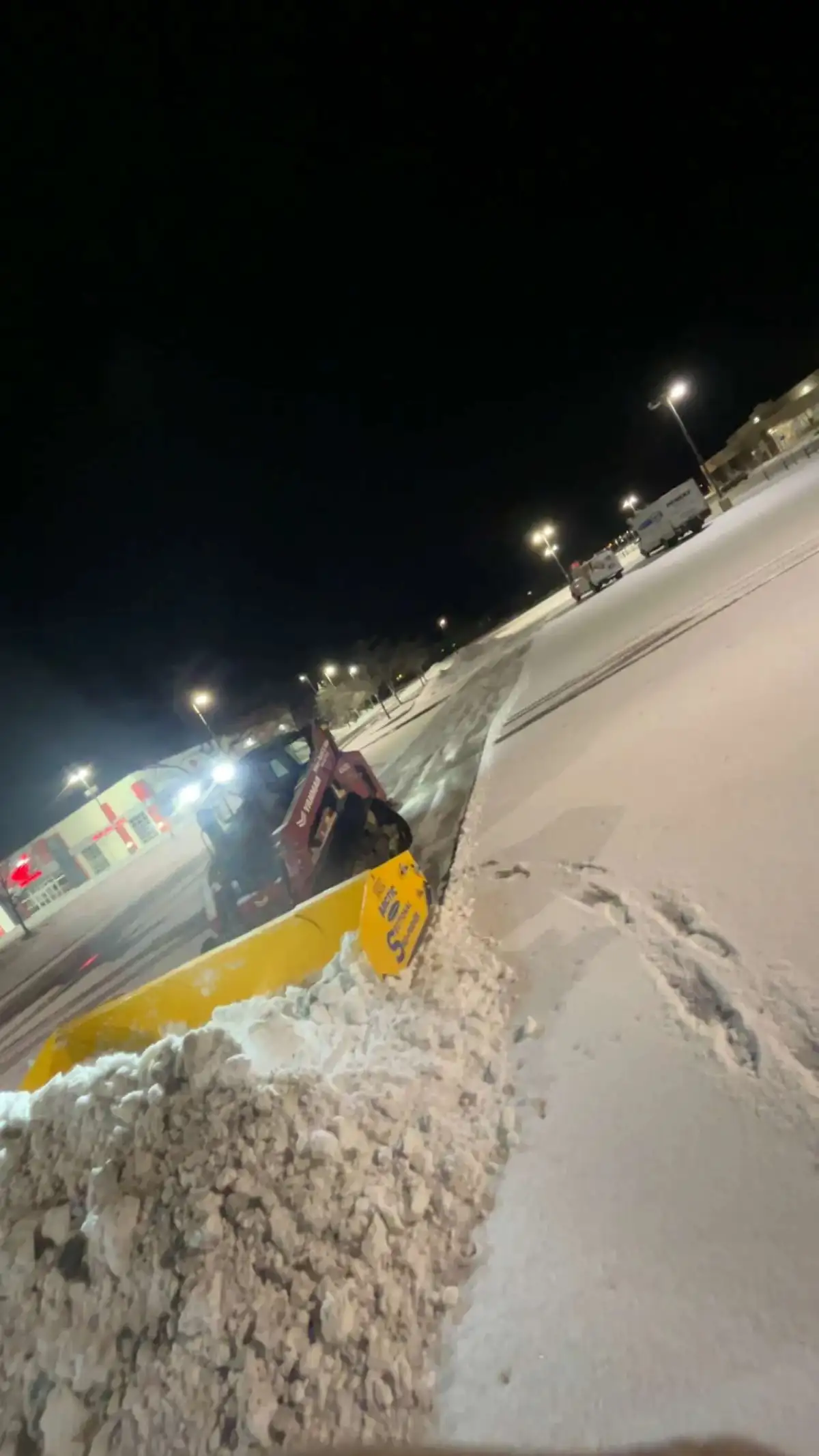 Raileys Services plow truck clearing a commercial parking lot during a snowstorm in Marysville, Ohio