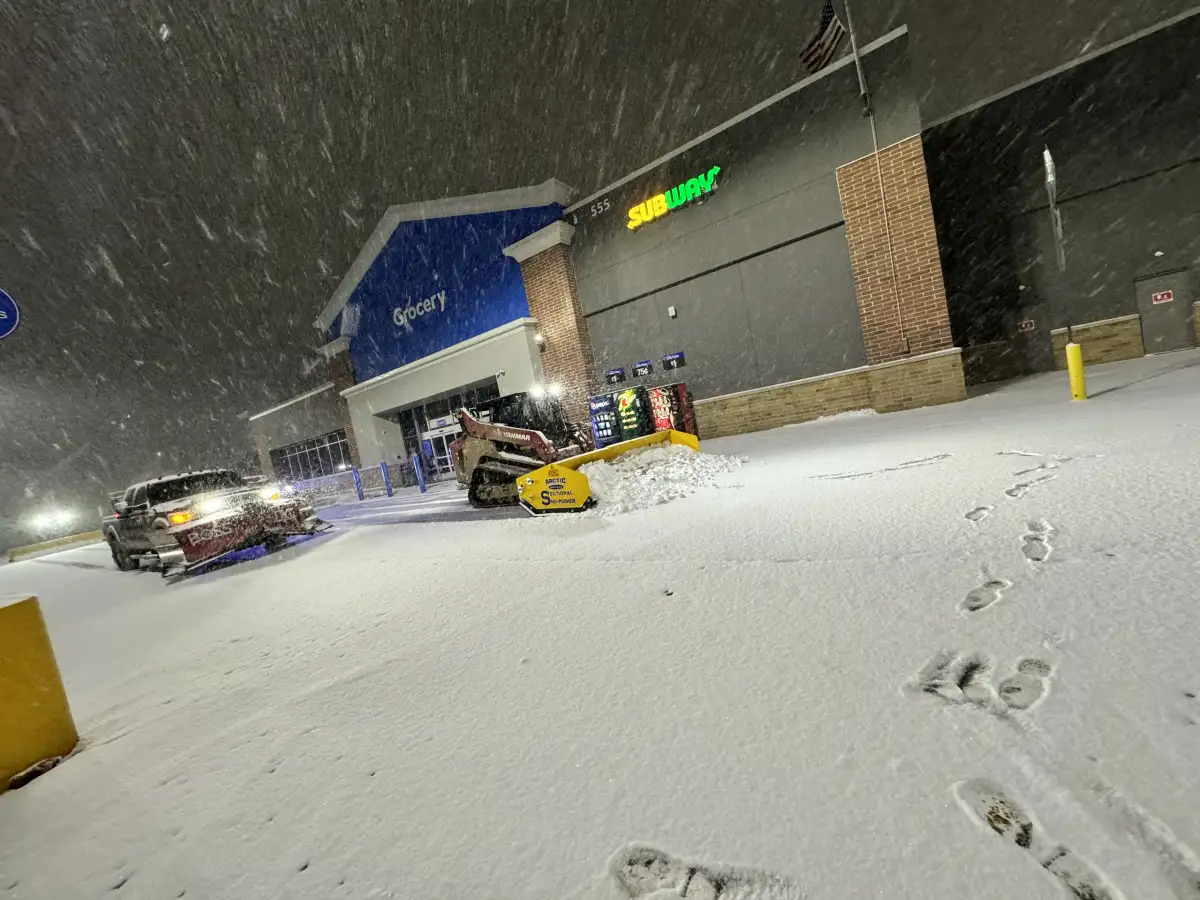 Sidewalk and entrance area being cleared and salted at a commercial property during winter